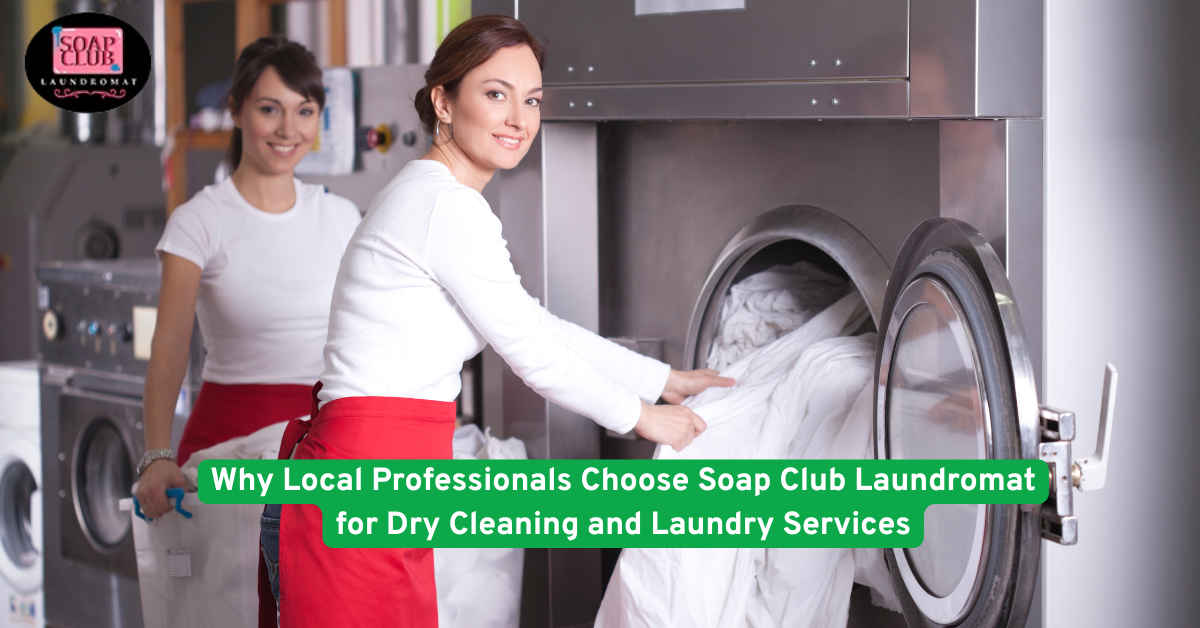 Two women using industrial laundry machines at a professional laundromat, loading white linens into a large front-load dryer.